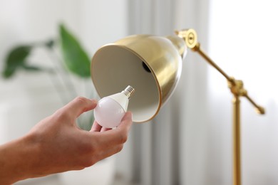 Photo of Man changing light bulb in lamp at home, closeup