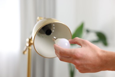 Photo of Man changing light bulb in lamp at home, closeup