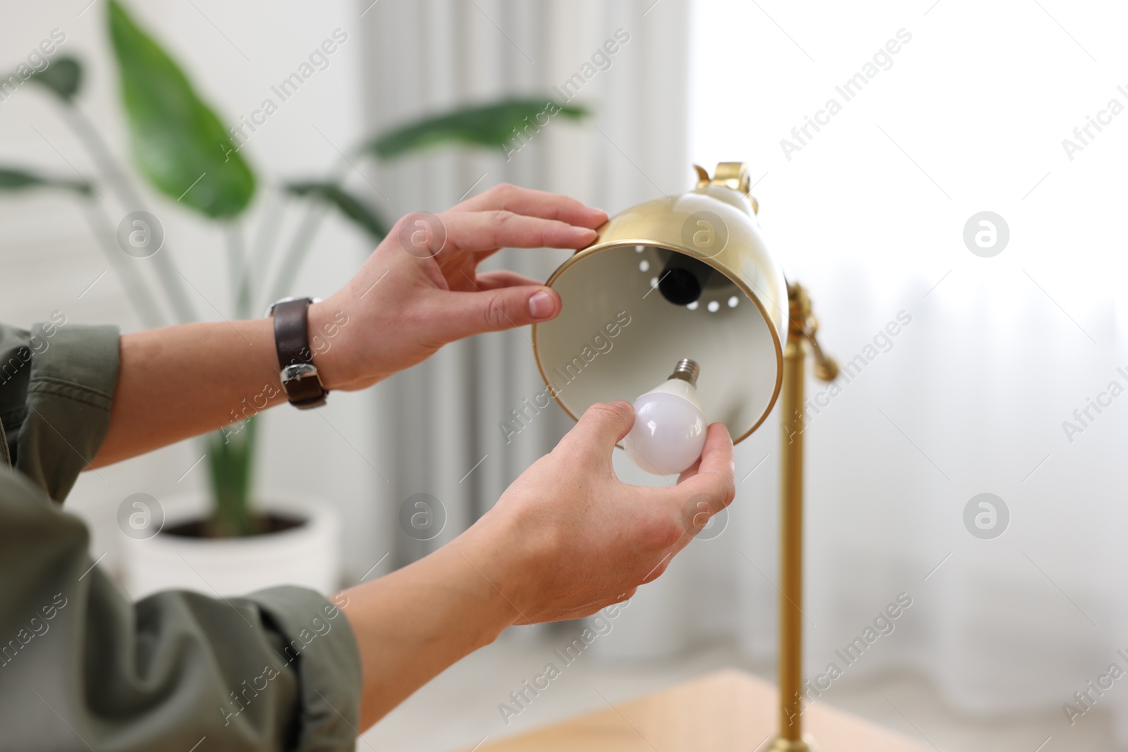 Photo of Man changing light bulb in lamp at home, closeup