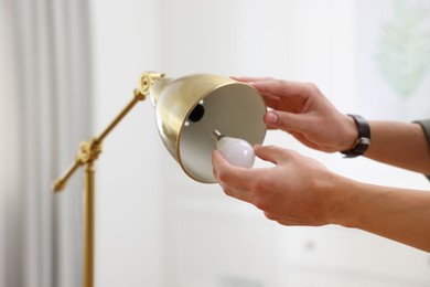 Photo of Man changing light bulb in lamp at home, closeup