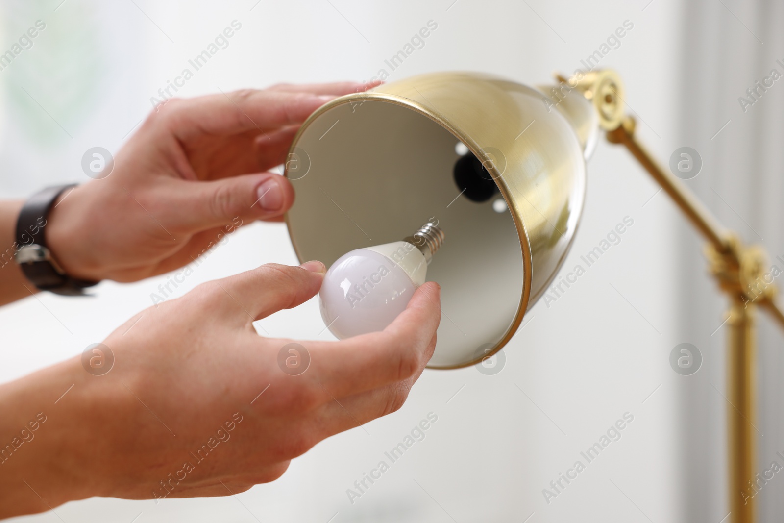 Photo of Man changing light bulb in lamp at home, closeup