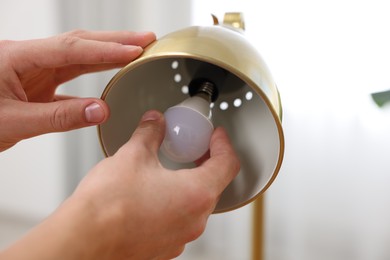 Photo of Man changing light bulb in lamp at home, closeup