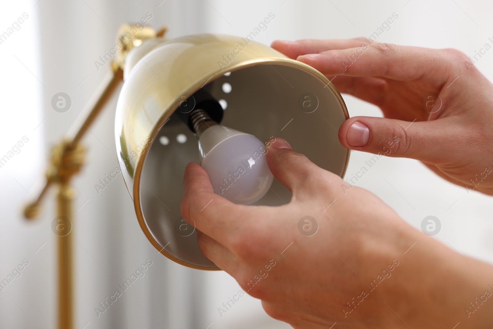 Photo of Man changing light bulb in lamp at home, closeup