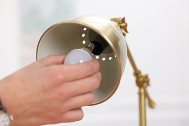 Photo of Man changing light bulb in lamp at home, closeup. Space for text