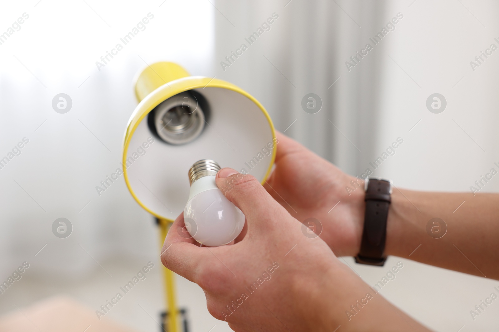 Photo of Man changing light bulb in lamp at home, closeup