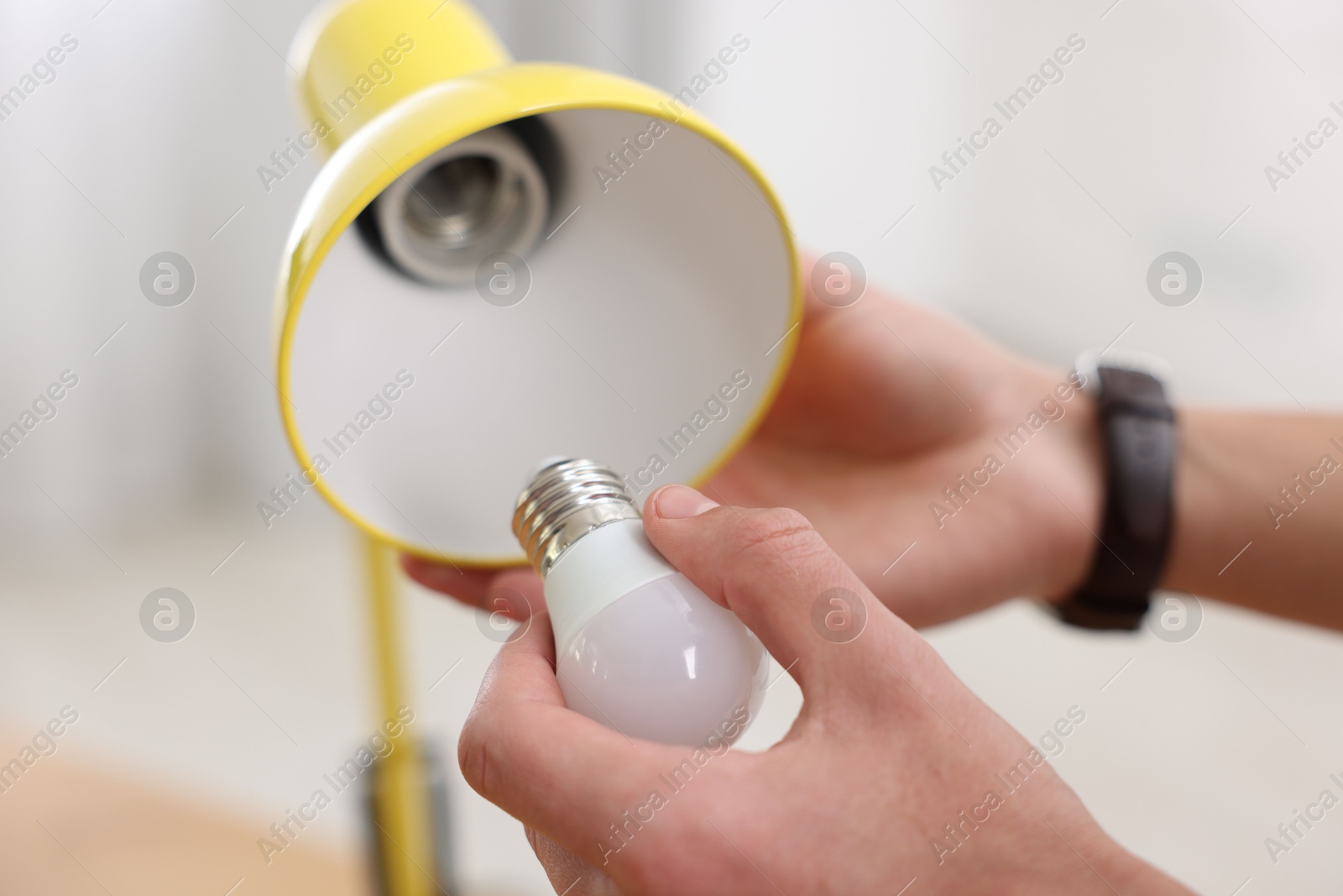 Photo of Man changing light bulb in lamp at home, closeup