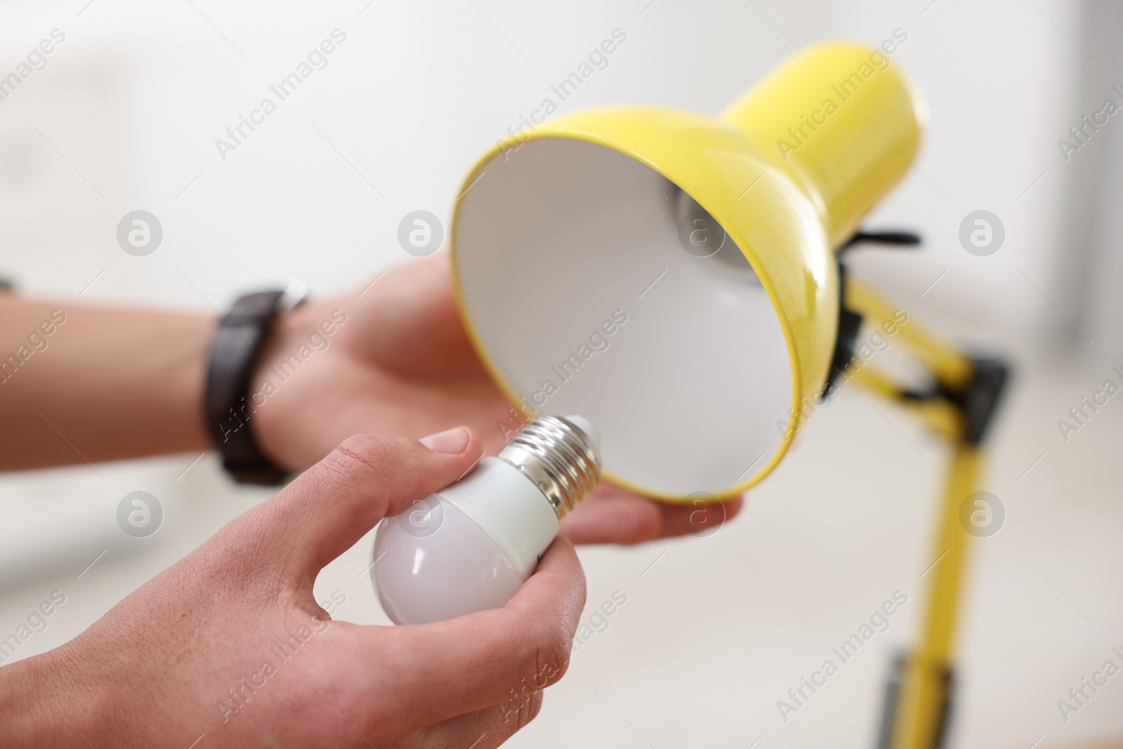 Photo of Man changing light bulb in lamp at home, closeup