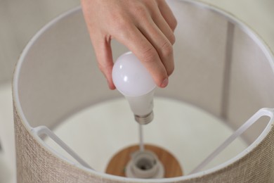 Photo of Man changing light bulb in lamp at home, closeup