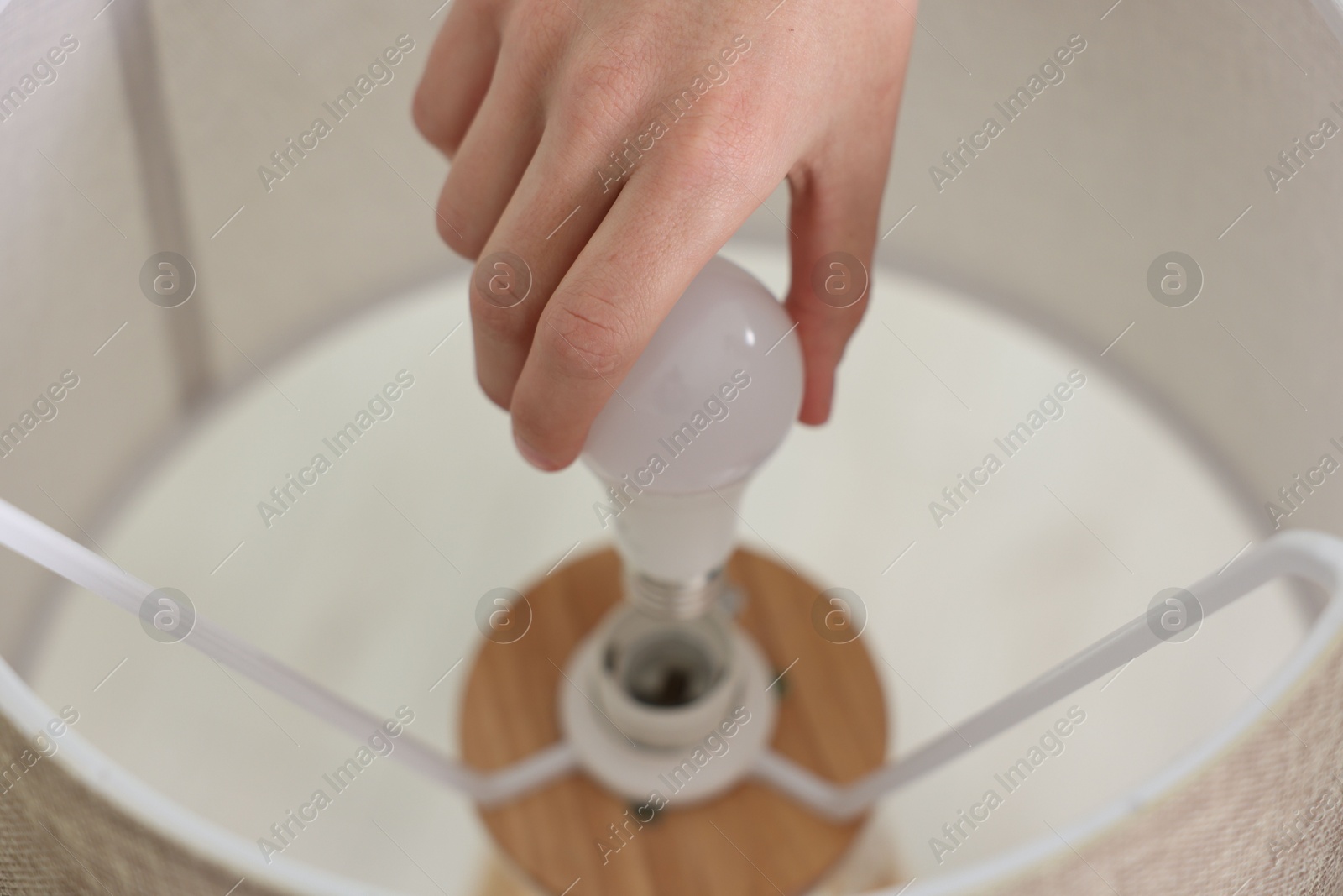 Photo of Man changing light bulb in lamp at home, closeup