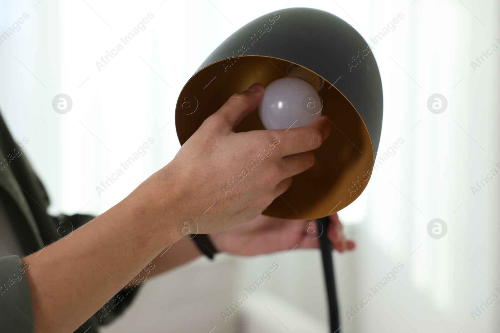 Photo of Man changing light bulb in lamp at home, closeup