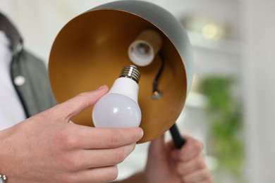 Photo of Man changing light bulb in lamp at home, closeup. Space for text