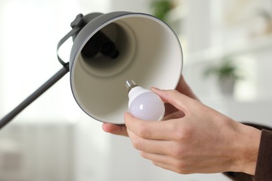 Photo of Man changing light bulb in lamp at home, closeup