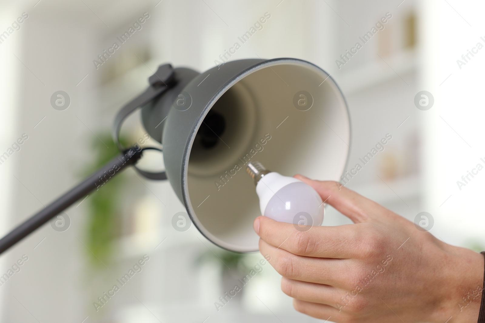 Photo of Man changing light bulb in lamp at home, closeup