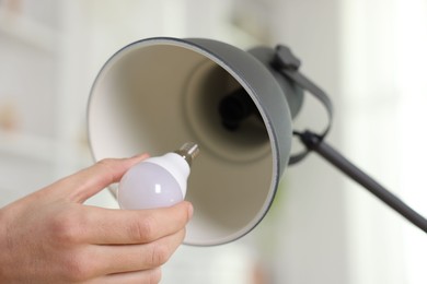 Photo of Man changing light bulb in lamp at home, closeup