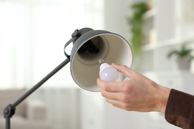 Photo of Man changing light bulb in lamp at home, closeup