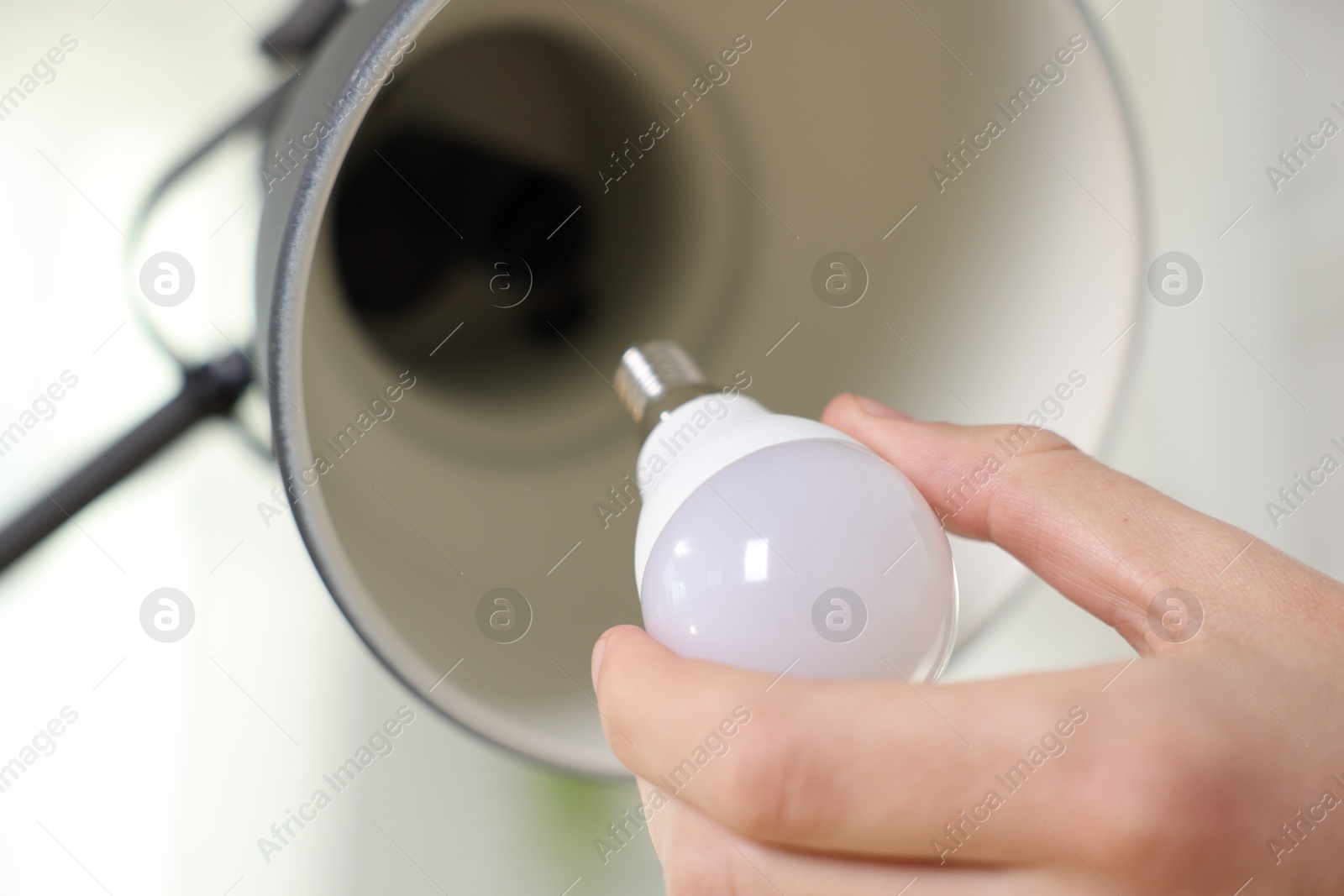 Photo of Man changing light bulb in lamp at home, closeup