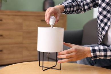 Photo of Man changing light bulb in lamp at home, closeup. Space for text