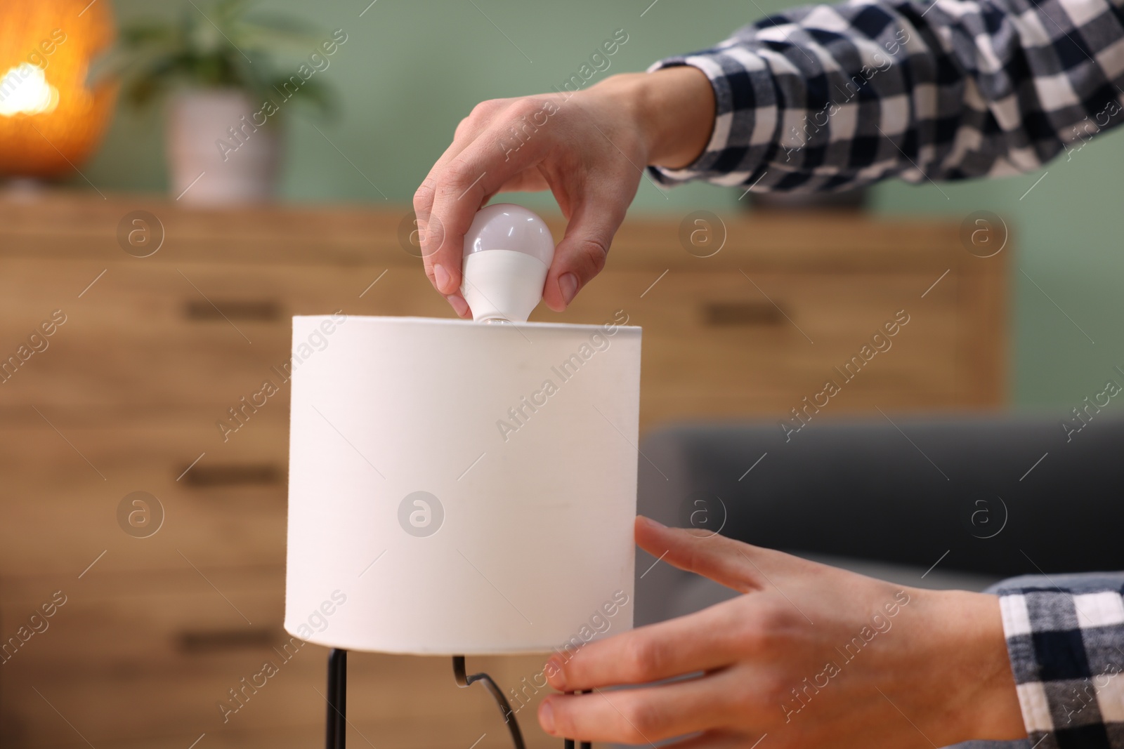 Photo of Man changing light bulb in lamp at home, closeup