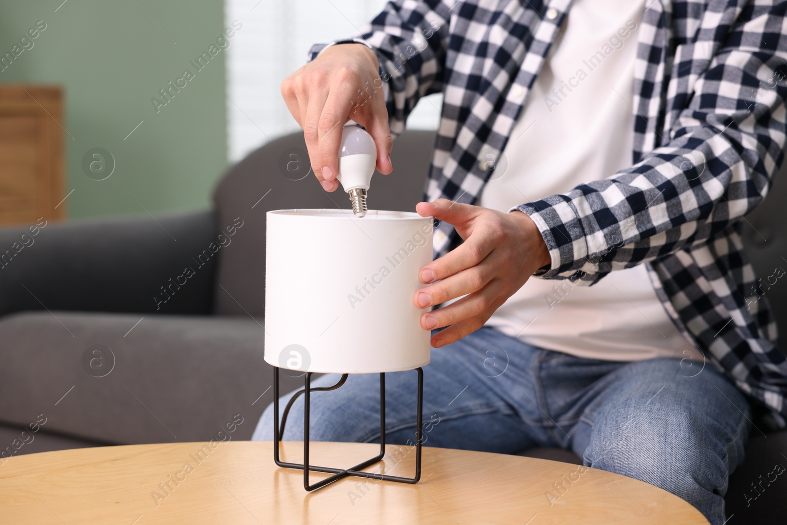 Photo of Man changing light bulb in lamp at home, closeup