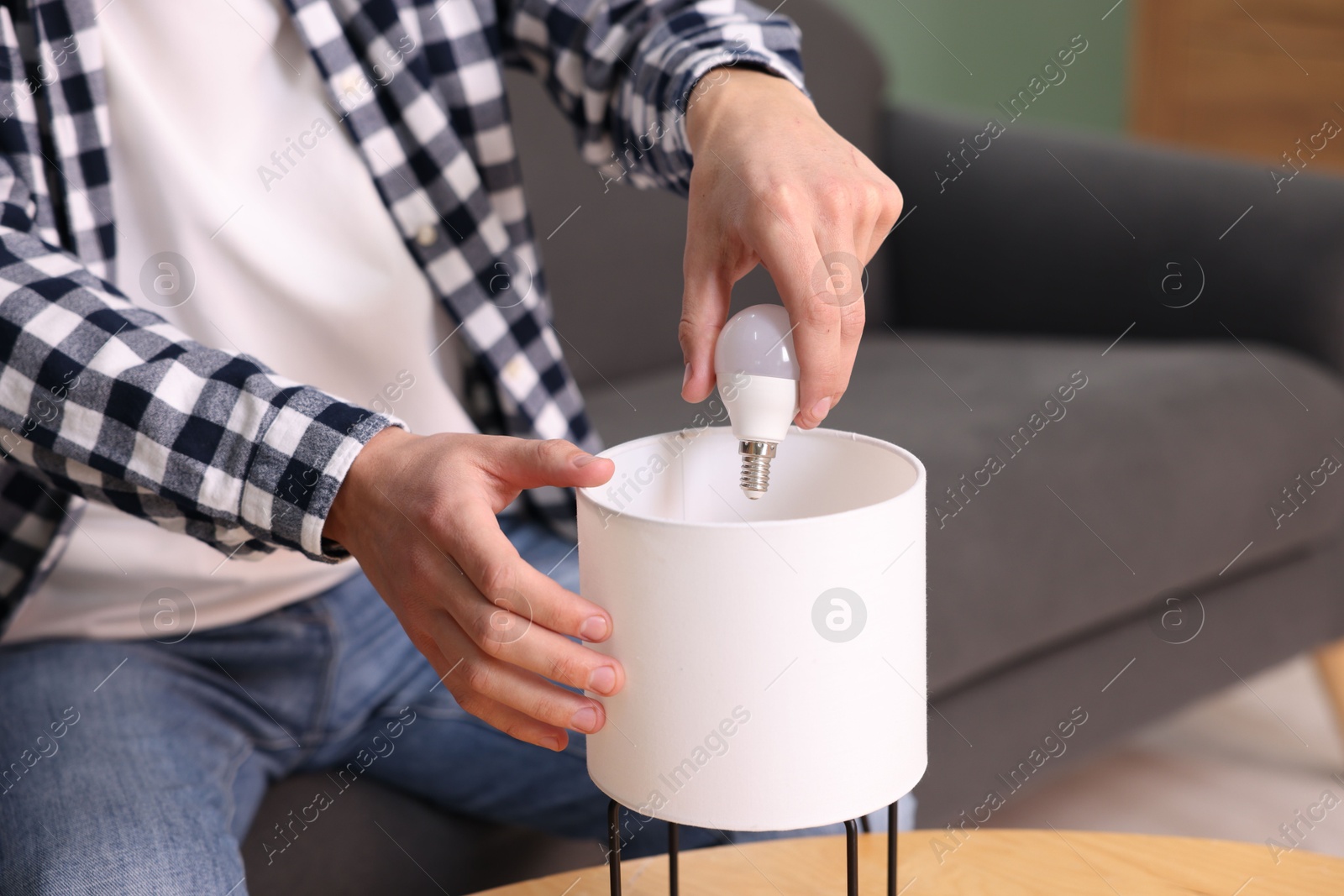 Photo of Man changing light bulb in lamp at home, closeup