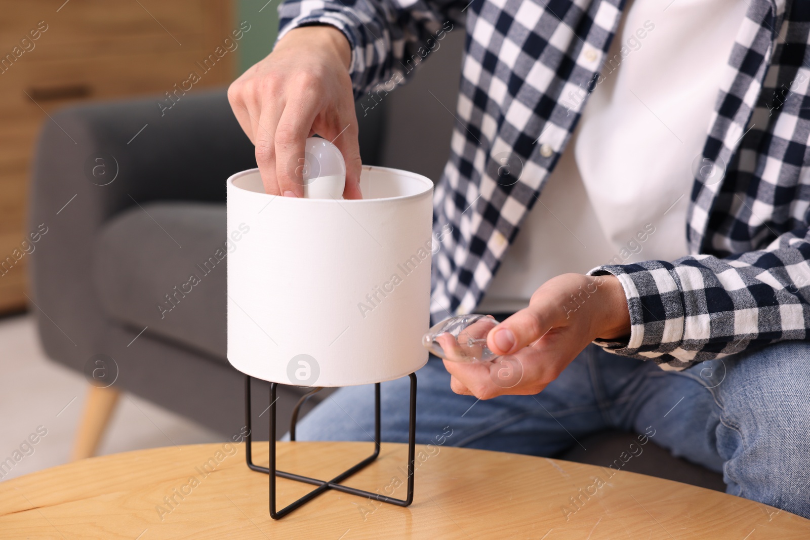 Photo of Man changing incandescent light bulb for fluorescent one in lamp at home, closeup