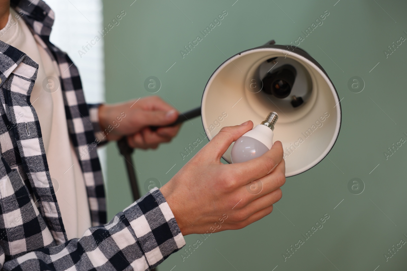 Photo of Man changing light bulb in lamp indoors