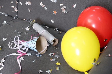 Photo of Shiny confetti, balloons and other party decor on sofa indoors