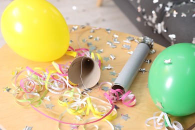 Photo of Shiny confetti, serpentine streamers and other party decor on wooden table, closeup