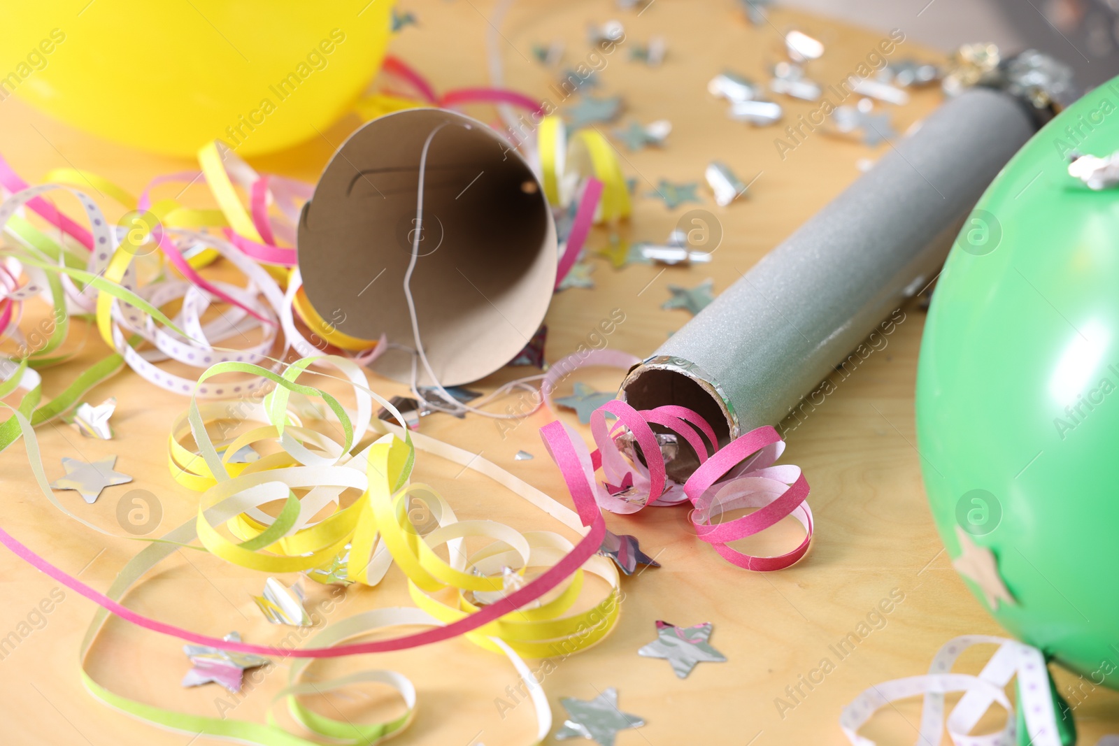 Photo of Confetti popper, serpentine streamers and other party decor on wooden table, closeup