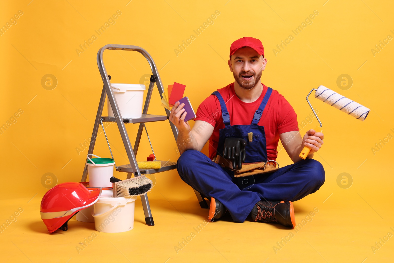 Photo of Professional painter with tools and supplies on orange background