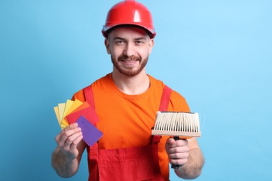 Photo of Professional painter with brush and color samples on light blue background