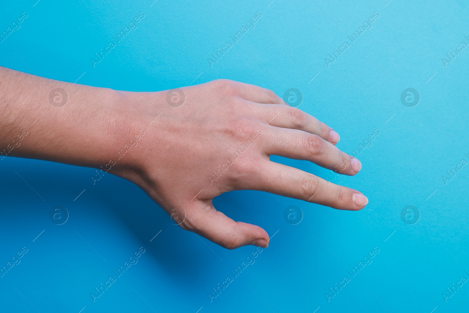 Photo of Woman with visible hand veins on light blue background, closeup