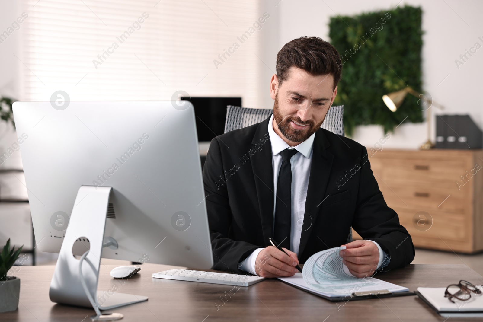 Photo of Man working with document at table in office