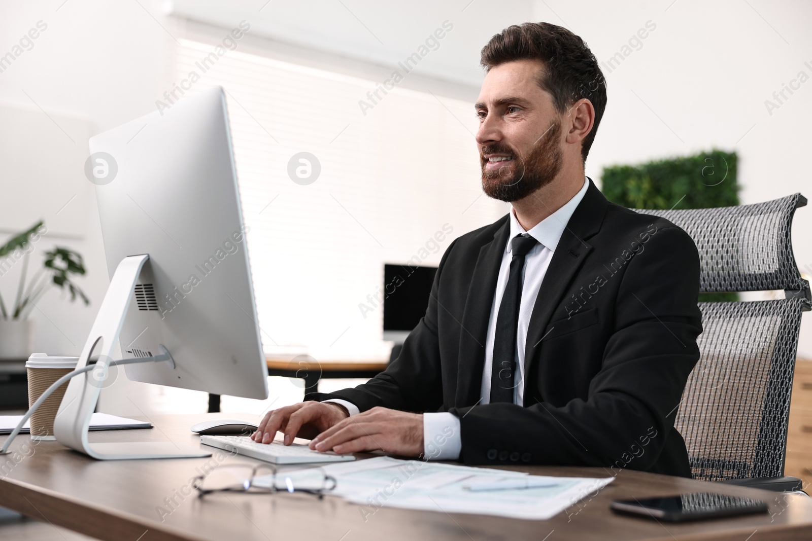 Photo of Man working on computer at table in office