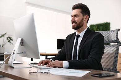 Photo of Man working on computer at table in office