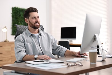 Photo of Man working on computer at table in office