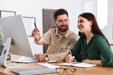 Photo of Colleagues working with computer at desk in office