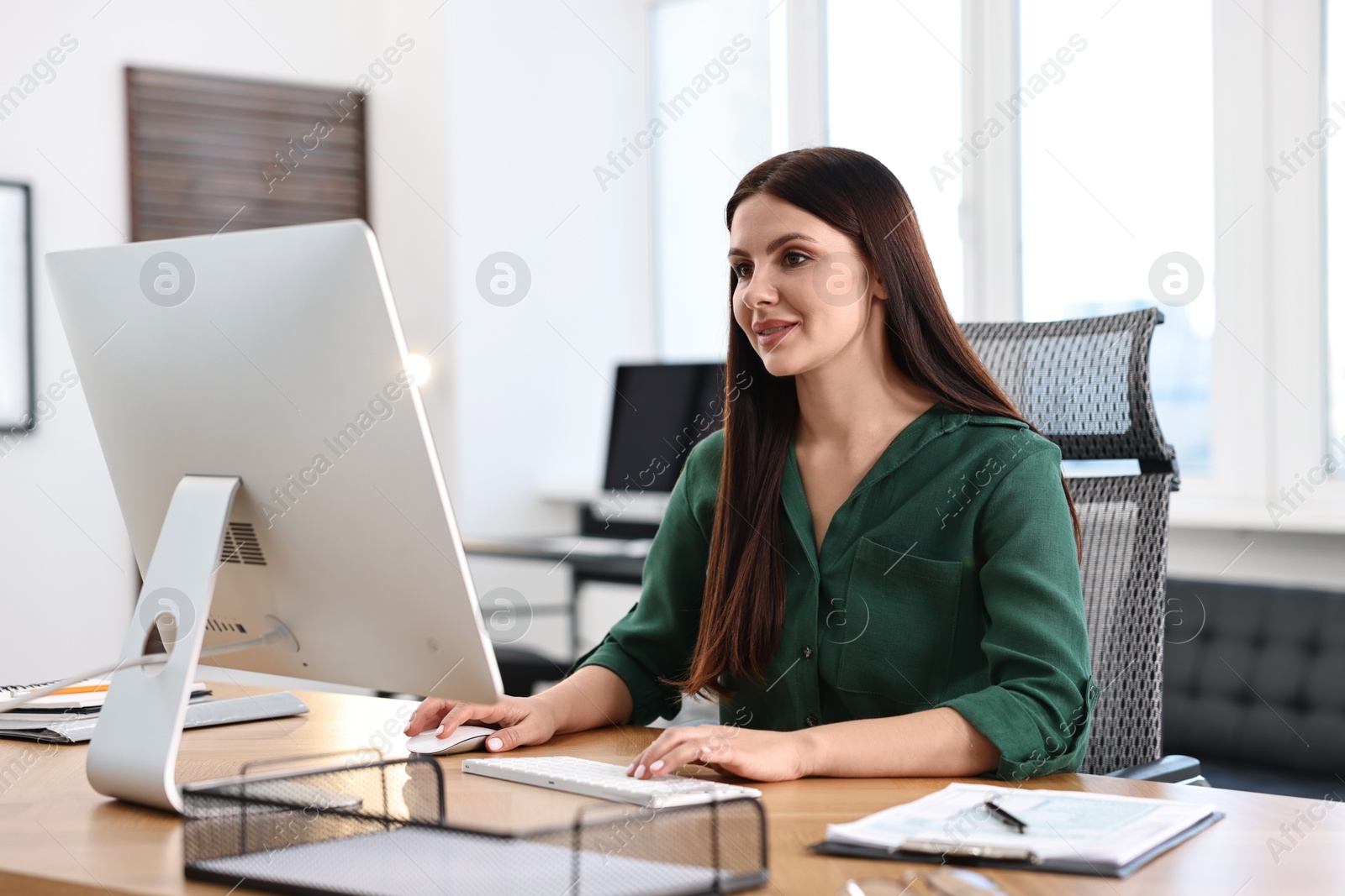 Photo of Woman working on computer at table in office