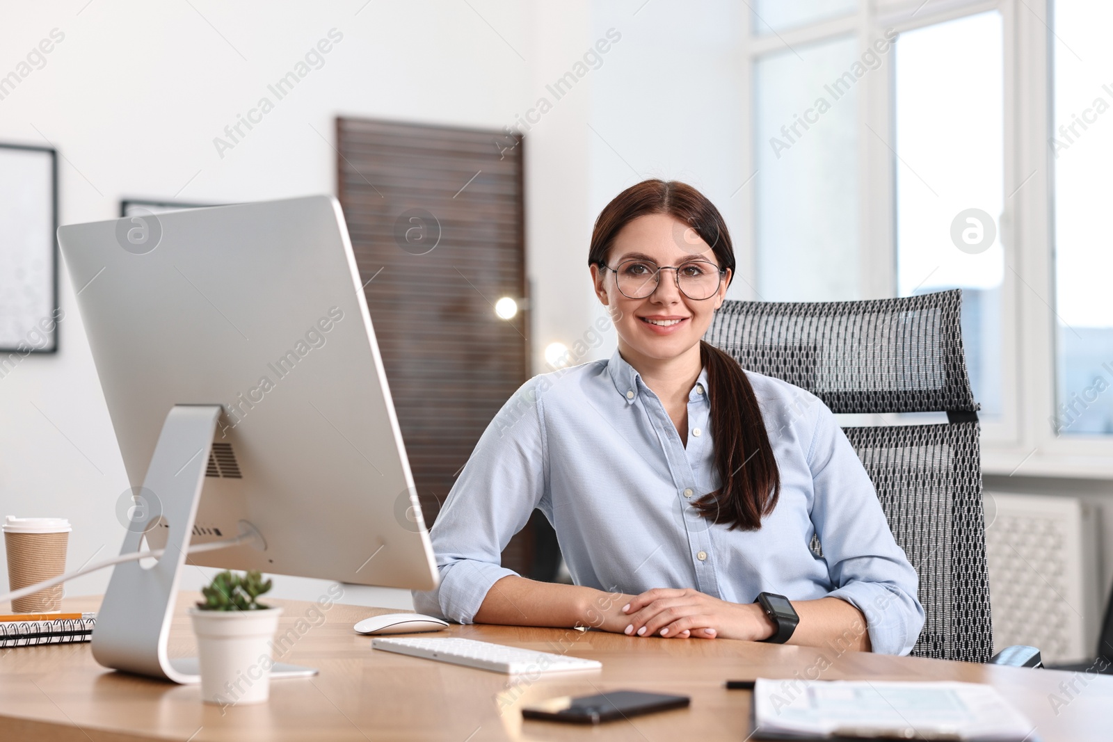 Photo of Portrait of woman at table with computer in office