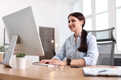 Photo of Woman working on computer at table in office