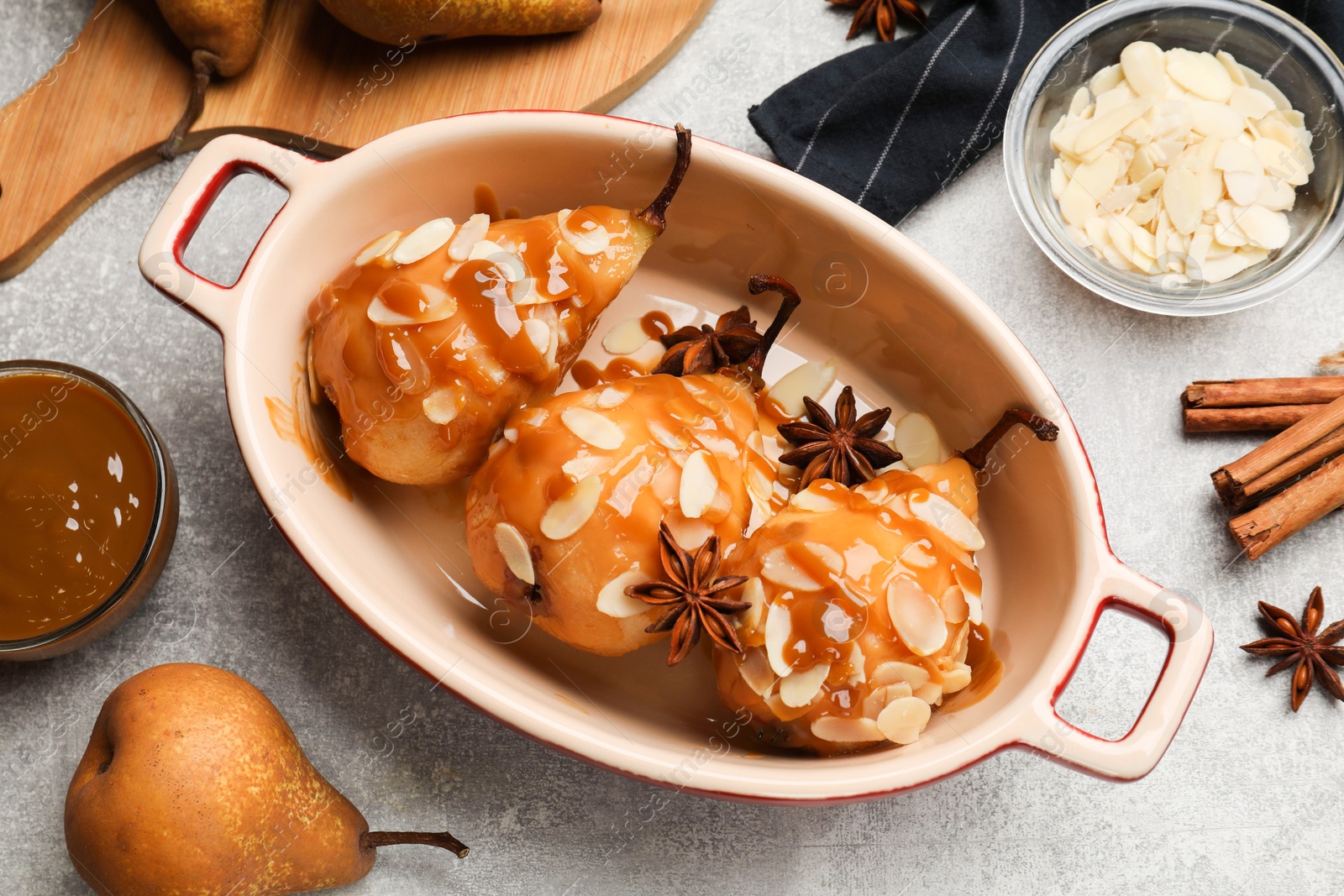 Photo of Delicious pears with caramel sauce, almond flakes and spices on grey table, top view