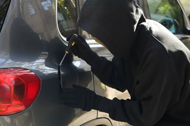 Photo of Thief with screwdriver opening fuel cap. Car hijacking