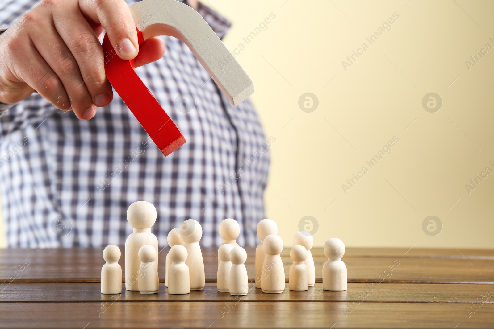 Photo of Man with magnet attracting game pieces at wooden table, closeup. Space for text