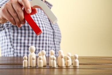 Photo of Man with magnet attracting game pieces at wooden table, closeup. Space for text