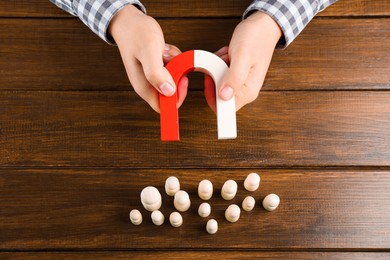 Photo of Man with magnet attracting game pieces at wooden table, above view