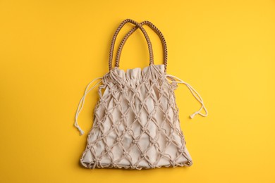 Photo of Macrame shopping bag on yellow background, top view