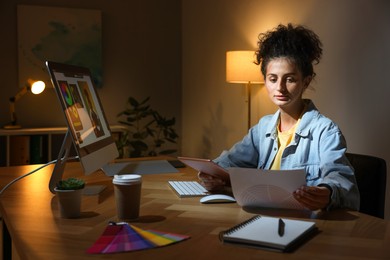 Photo of Designer with tablet and color palette working indoors at night