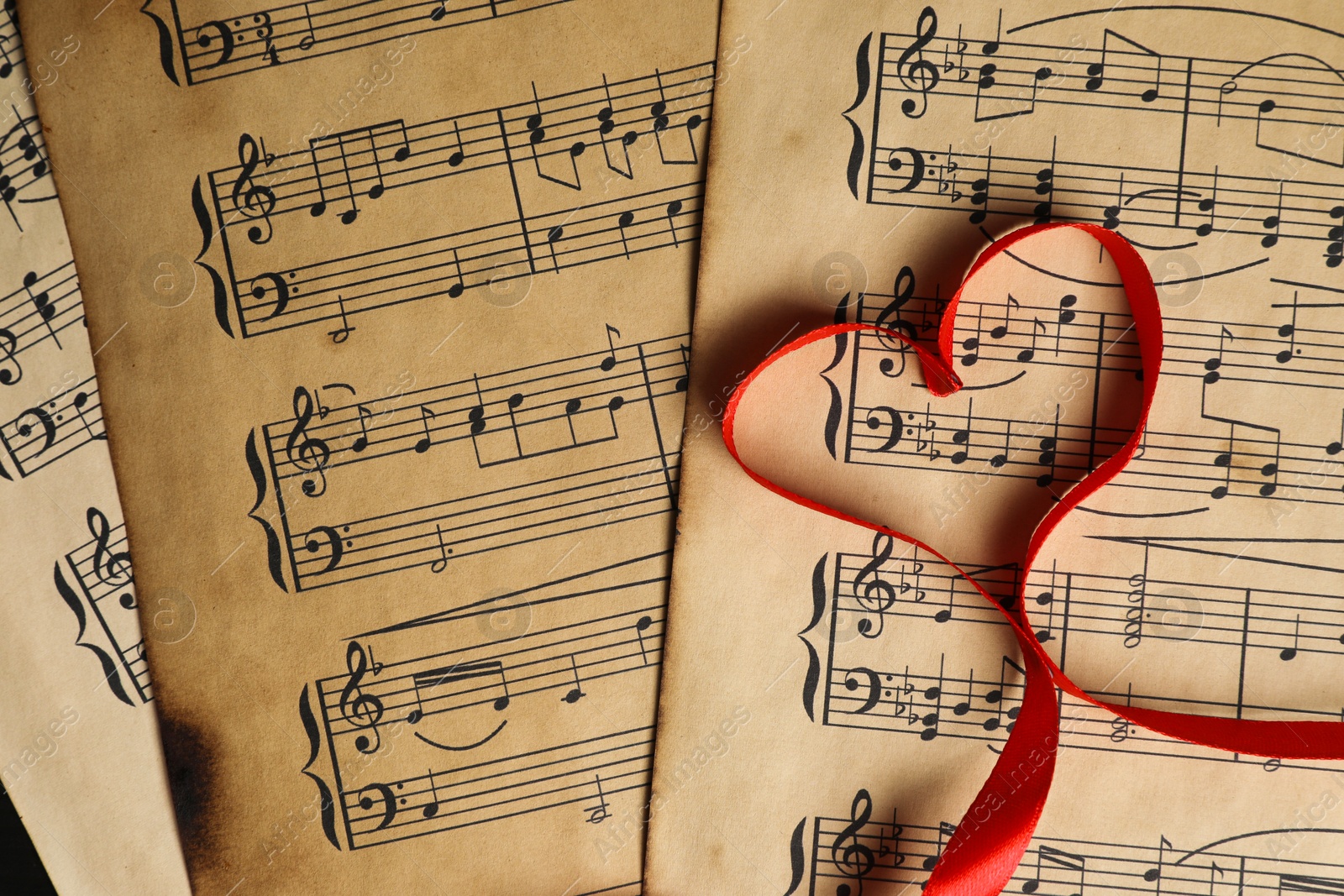 Photo of Heart shaped ribbon on musical notes, top view