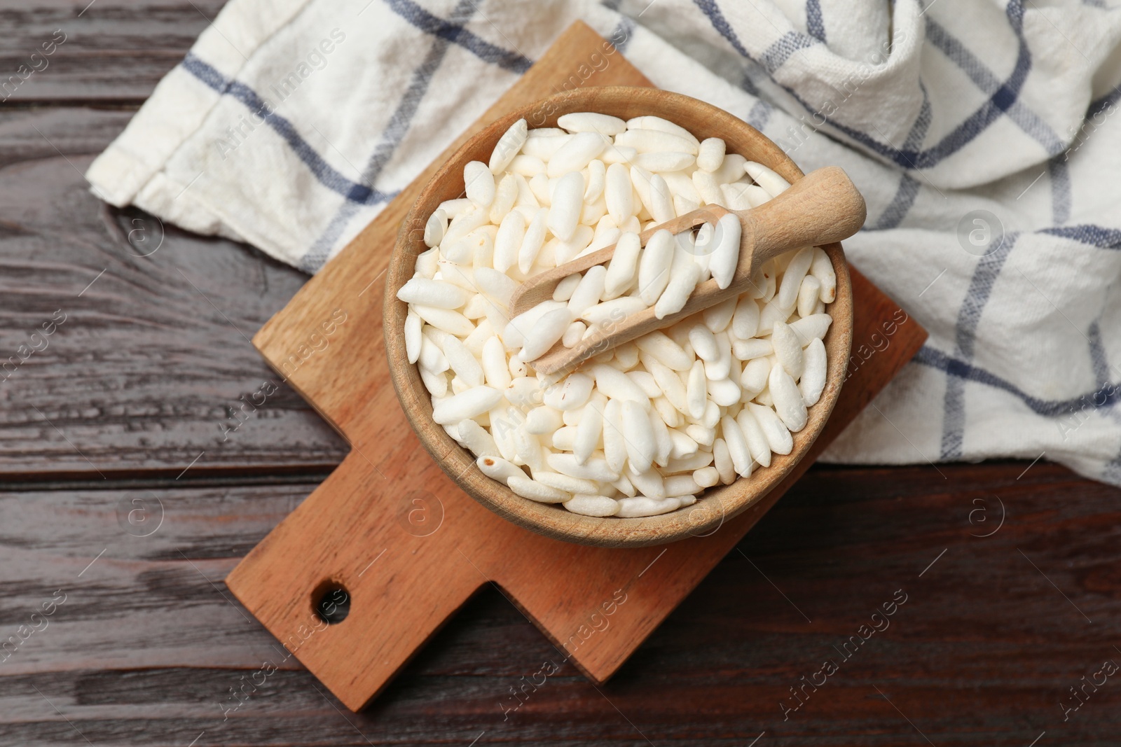 Photo of Puffed rice in bowl and scoop on wooden table, top view