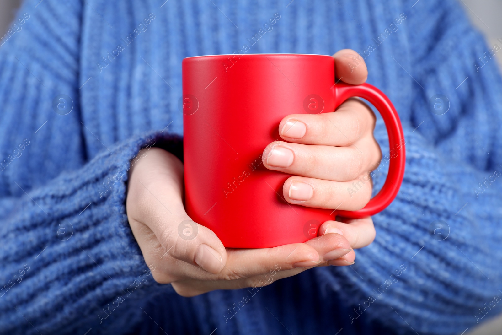 Photo of Woman holding blank red ceramic mug, closeup. Mockup for design